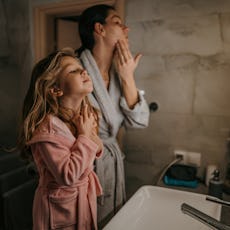 A woman and her daughter look in the mirror at their skin.