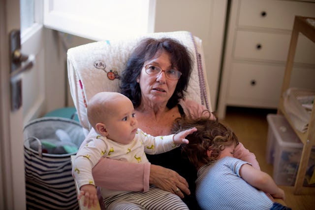 A grandma sits with her two grandkids in a rocking chair.