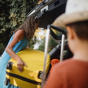 Mother packing car with two small children. Summer vacation concept, road trip