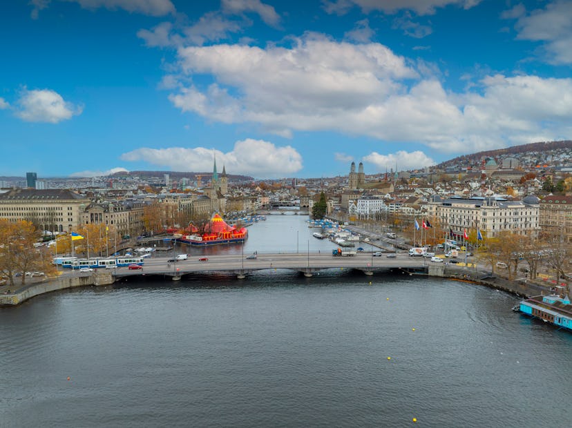 Aerial footage of the Zurich old town where the Limmat river joins lake Zurich with tramway running ...