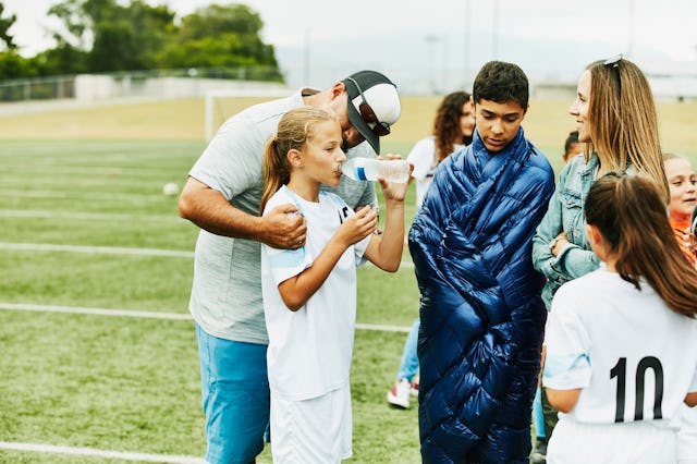 Parents talk to their daughter during a soccer game.