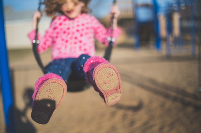 A little girl who is autistic on a swing at a playground