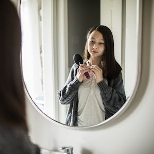 A teen looks at their body in the mirror.