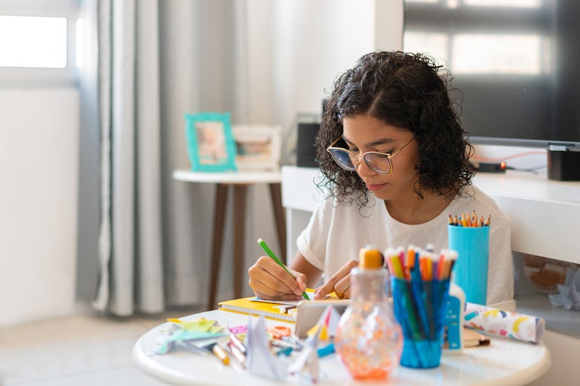 A girl does art in her bedroom.