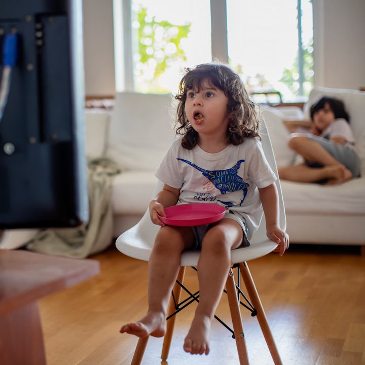 A little girl being shocked by something on the TV and another child laying on the couch in the back...