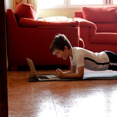 A young boy holds a plank while exercising.