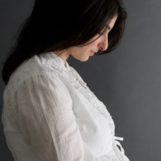 A worried pregnant woman with long dark hair looking at her belly