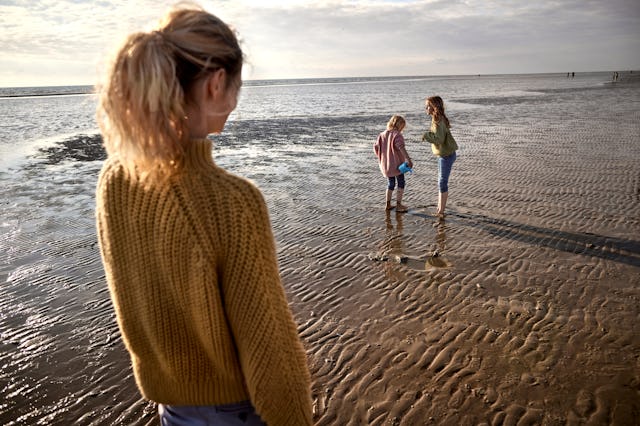 Mother watching her kids playing on the beach 