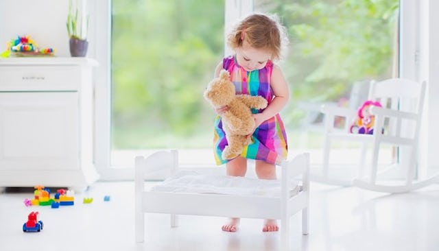 Little Girl Putting A Teddybear To Bed