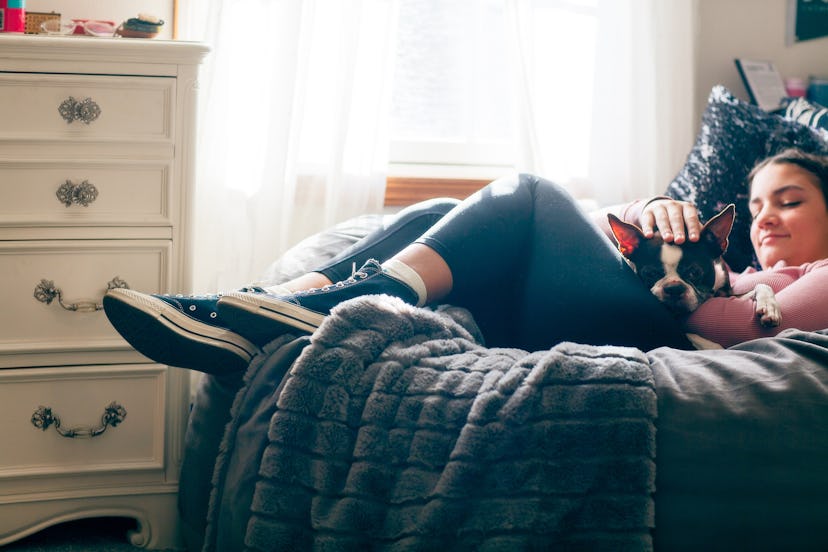 A teen sits in a bean bag with a dog.