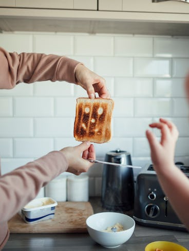 A woman holds up a piece of burnt toast to show her son.