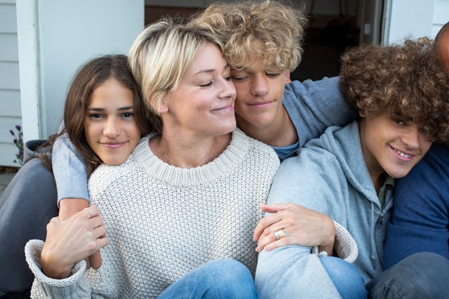 A woman hugged by her children who needs to watch what she says about her her body around her sons