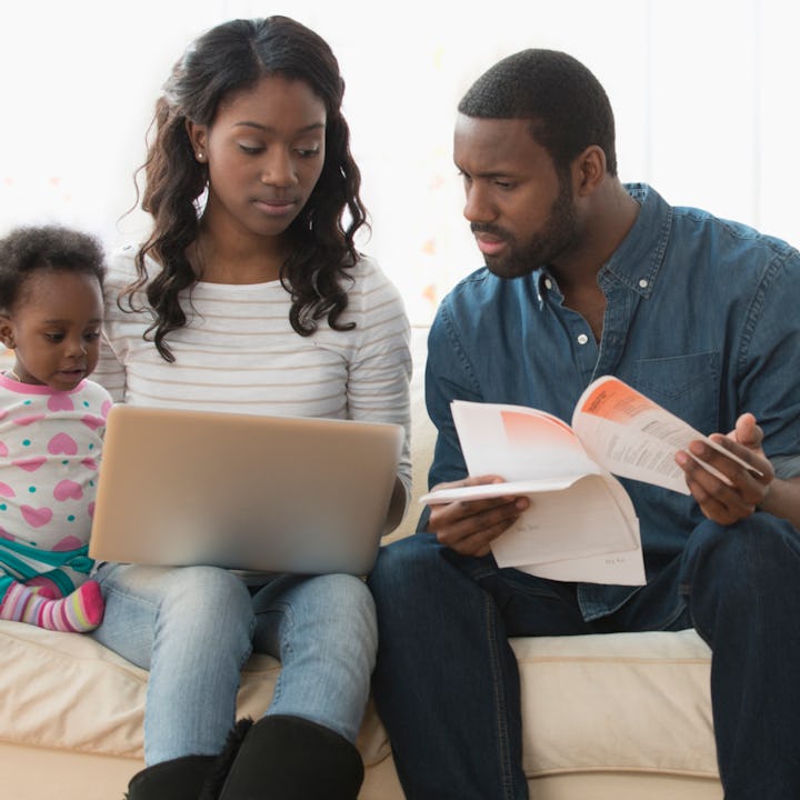 Two parents paying bills on a laptop, looking concerned. Inflation has caused the cost of raising a ...