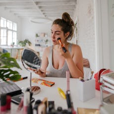 A woman applies makeup to her face.