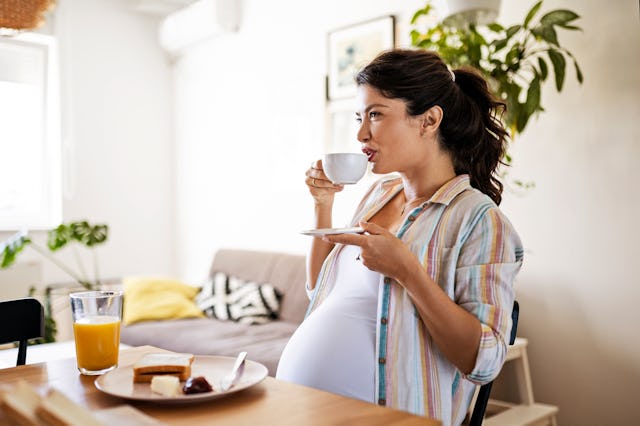 Young pregnant woman alone in her kitchen enjoying a breakfast. A new study suggests that even the s...