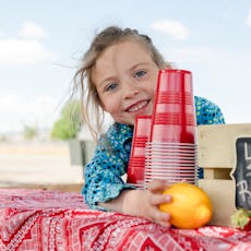 A young girl sells lemonade at her lemonade stand.