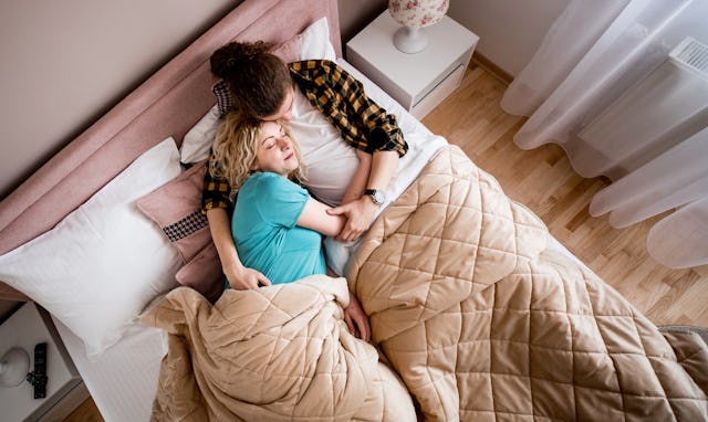 A man and woman sleep under a weighted blanket.