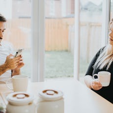 A couple looks tense at the breakfast table.