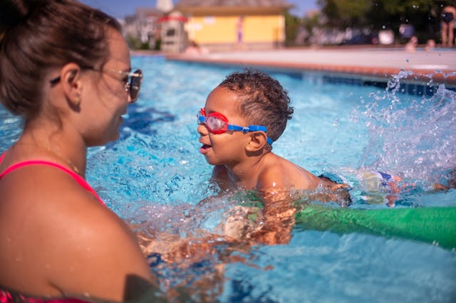 A swim instructor teaches a 3-year-old to swim.