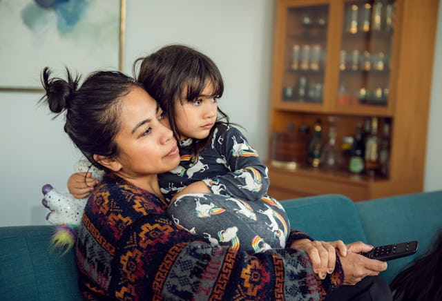 A mom watches TV with her daughter.