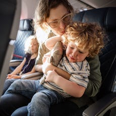 A mother comforts her child on an airplane.