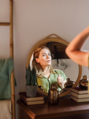 A woman looks at herself in the mirror.