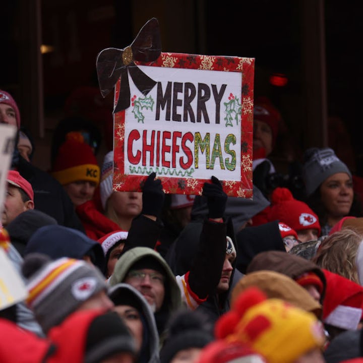 Crowd of Kansas City Chiefs fans with a sign reading "Merry Chiefsmas" at a football game.