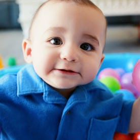 A baby sits in a kiddie pool filled with balls.