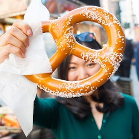 A woman holds up a salty pretzel.