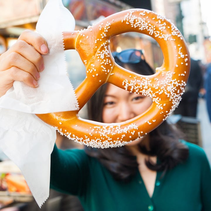 A woman holds up a salty pretzel.