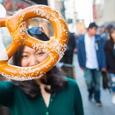 A woman holds up a salty pretzel.