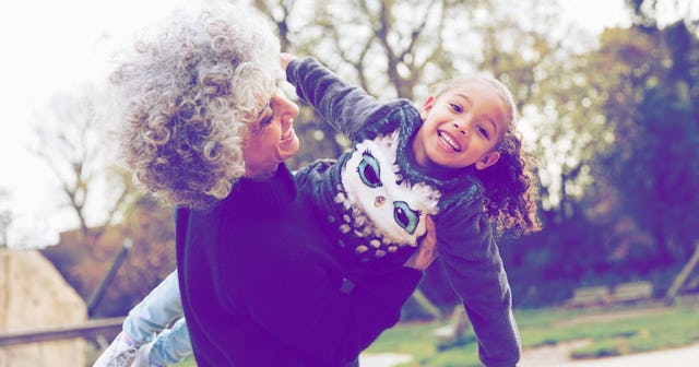 A grandmother raising her granddaughter while playing with her and both are smiling