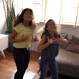 Mother filming teenager daughters dancing at home