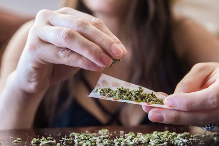 A woman preparing a cannabis joint for smoking